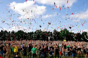 Crowd of people at an outdoor festival with items being thrown in the air.