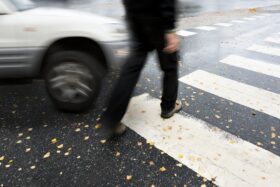 Pedestrian walking in a crosswalk with a car about to hit them.