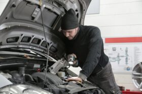 Mechanic looks under the open hood of a car.