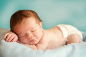 Sleeping baby laying on a blanket.