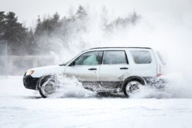 White car driving on a snowy road.